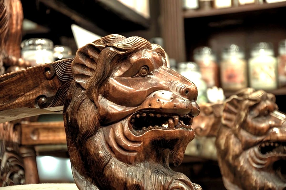 Carved wooden lion chair arms with candle jars behind